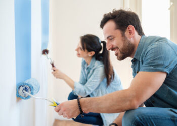 Junges Paar streicht Wände in seinem neuen Haus, do it yourself-Konzept.